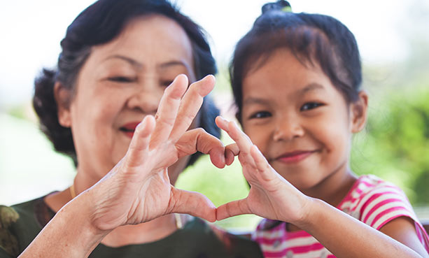 grandmother and grandchild making a heart with fingers