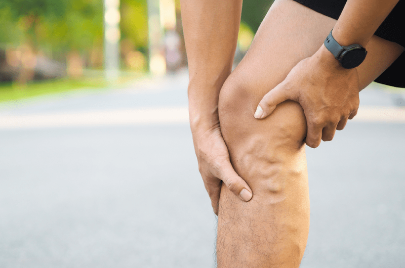 man holding leg with varicose veins