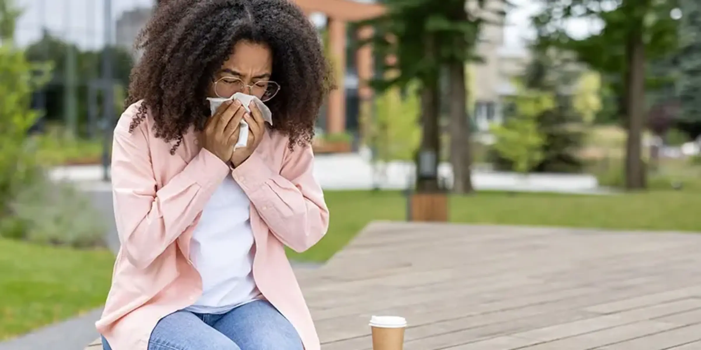 African American woman sneezing while sitting outside