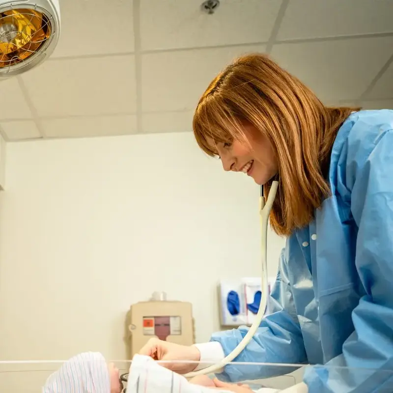 Nurse checks on infant in incubator