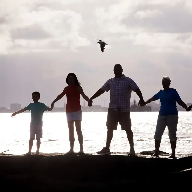 Family holds hands on beach