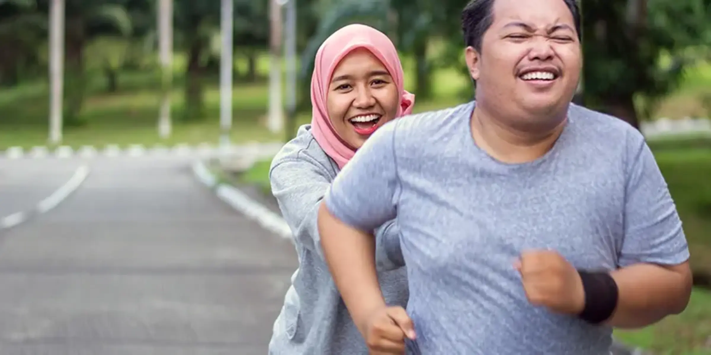 young Muslim women encouraging Asian male friend running in the park