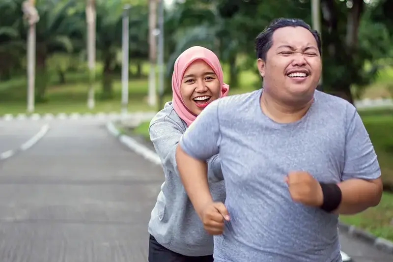 young Muslim women encouraging Asian male friend running in the park