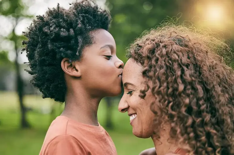 Boy kissing mother on forehead