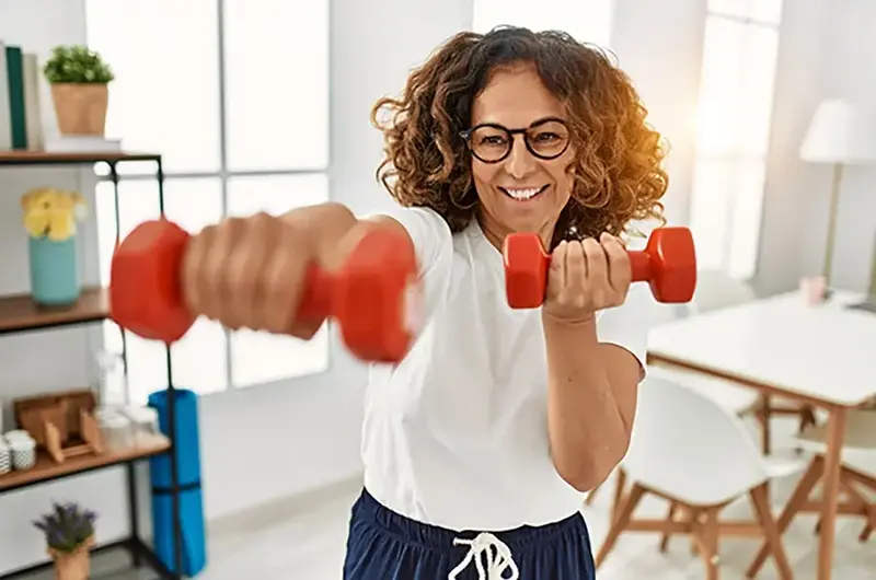 Middle age hispanic woman training using dumbbells