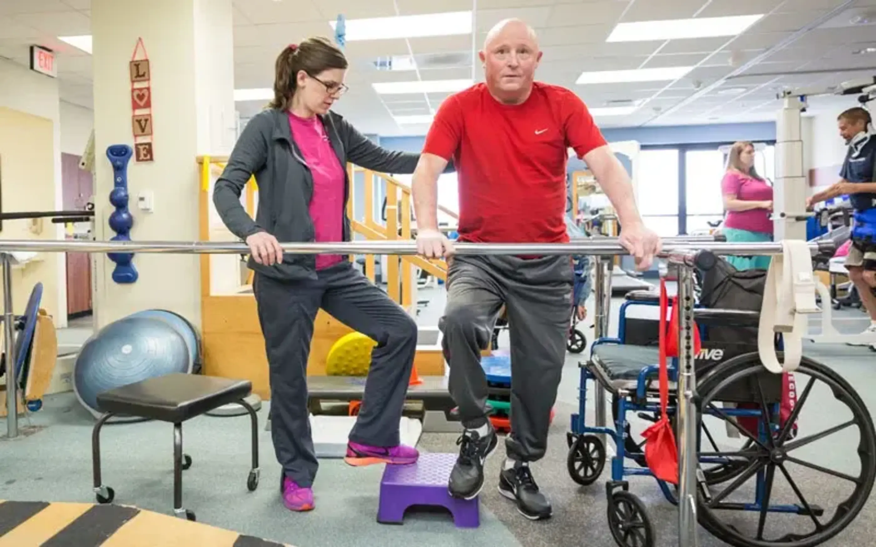 physical therapist with patient in gym