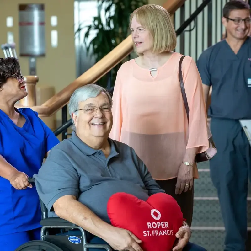Patient in wheelchair holds heart pillow