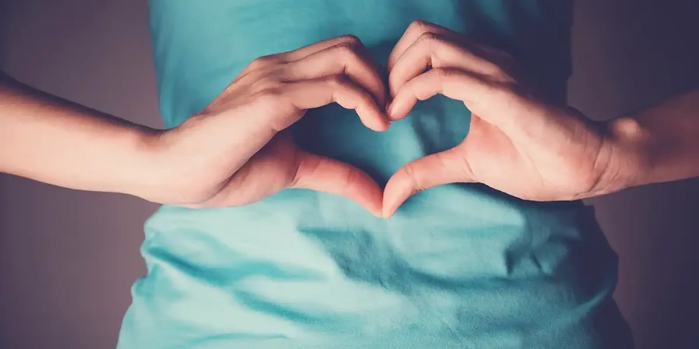 Woman hands making a heart shape on her stomach