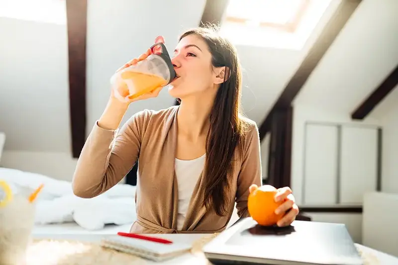 woman drinking orange juice in home office