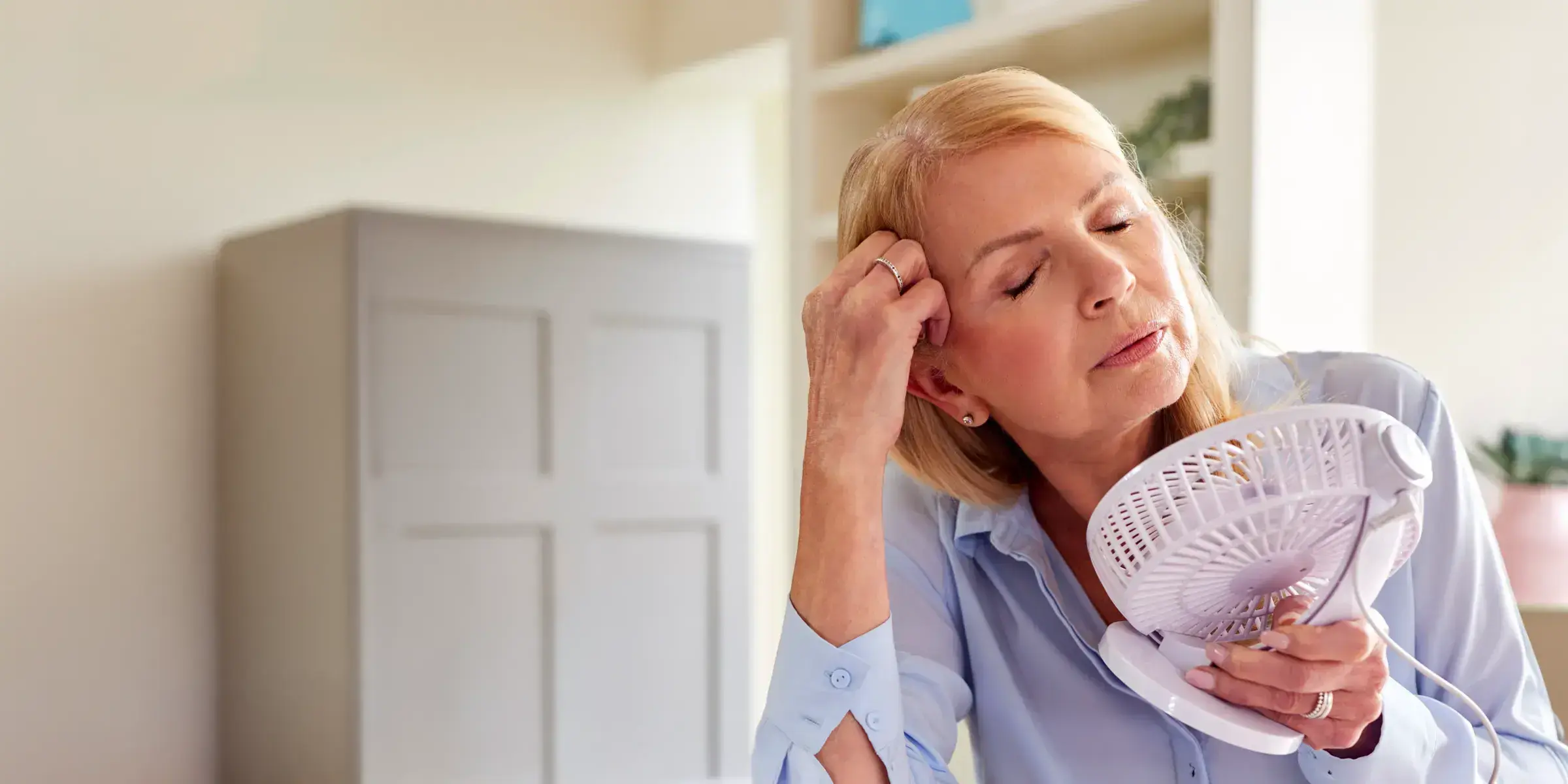 Woman holds fan near face