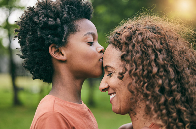 Photo of a child kissing his mother on the forehead