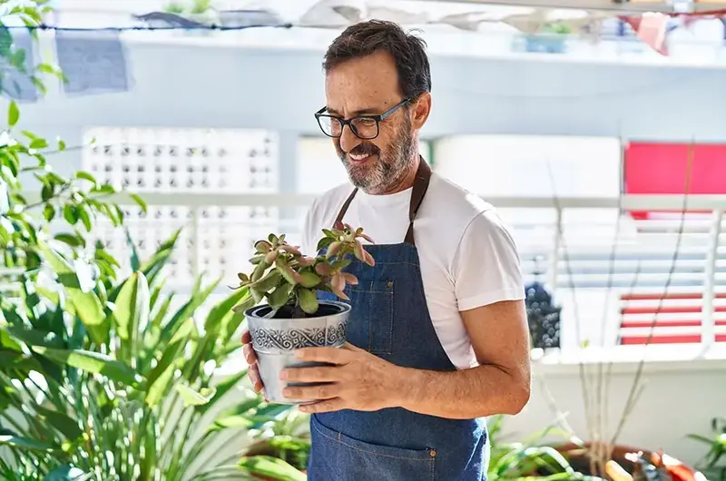 Middle age man smiling and holding plant pot