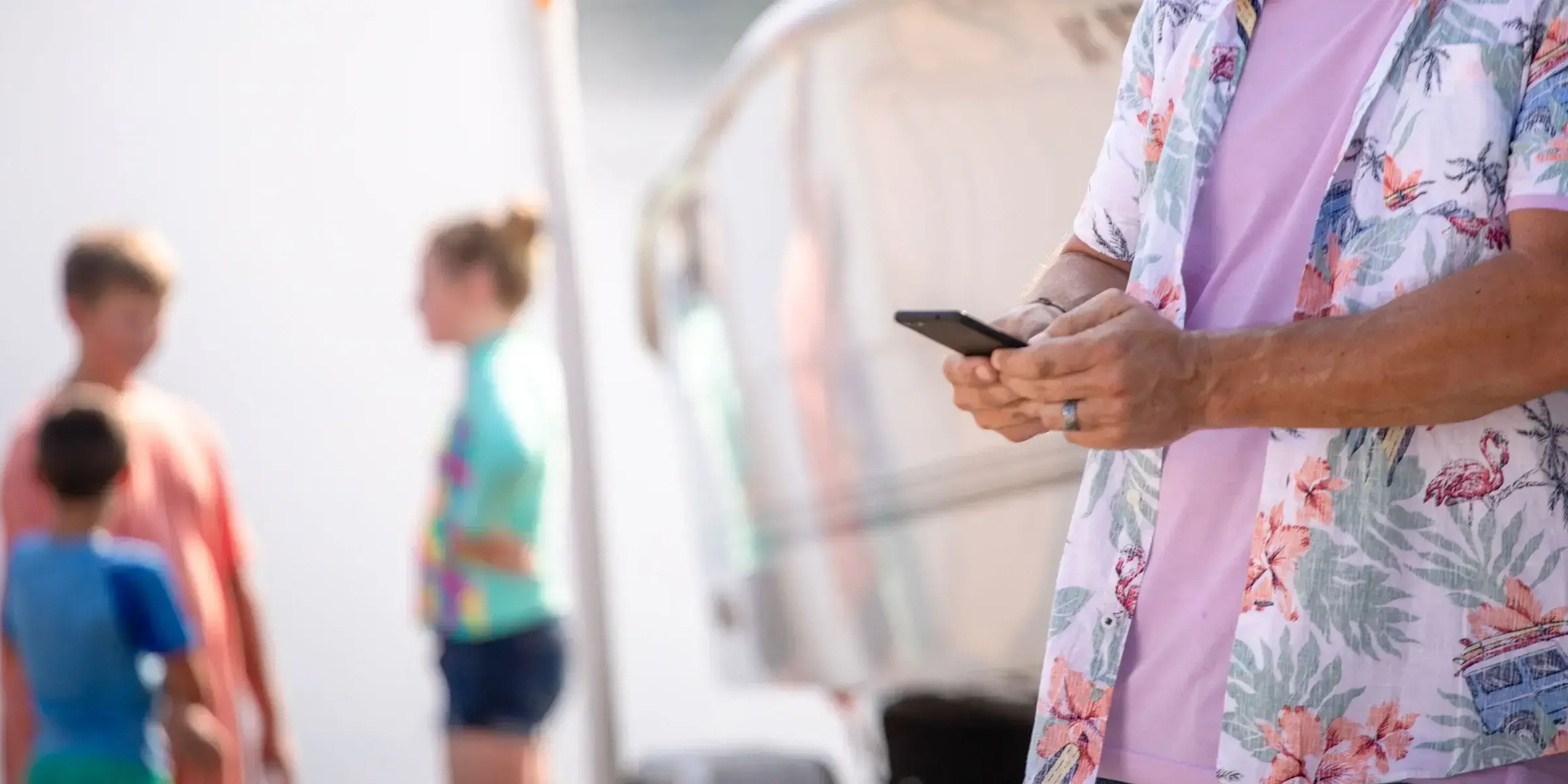 Man holds cell phone by boat
