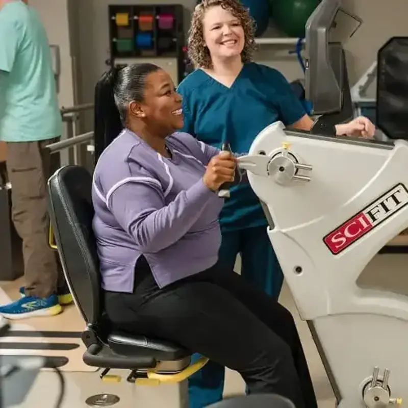 Nurse with cardiac rehabilitation patient using exercise equipment.