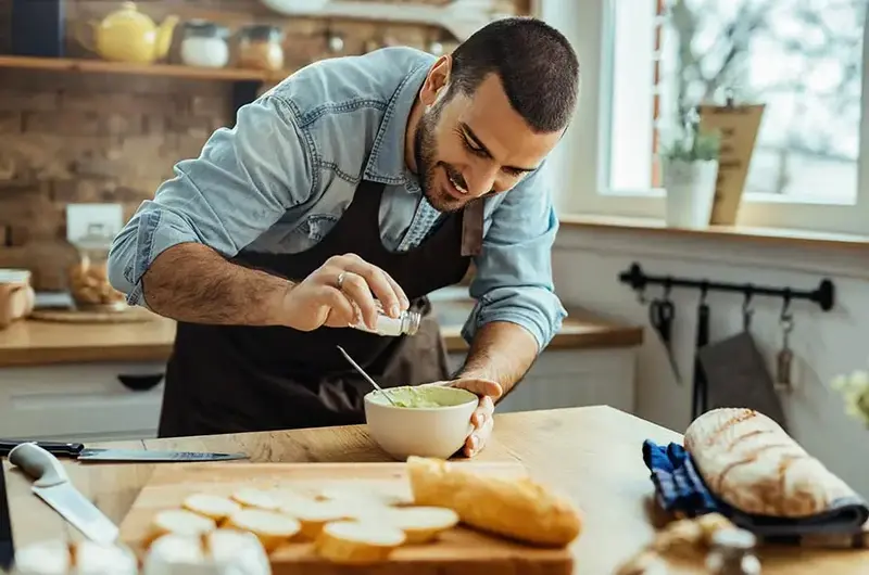 man adding salt to a dish