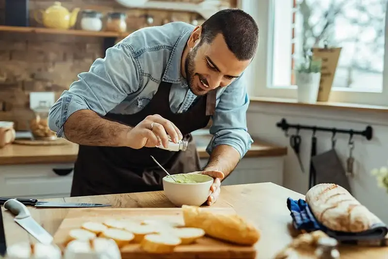 man adding salt to a dish