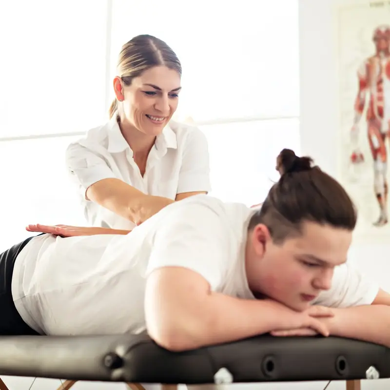 injured young male athlete with therapist