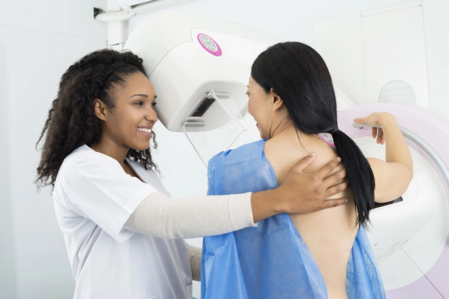 Happy Doctor Assisting Woman Undergoing Mammogram X-ray Test