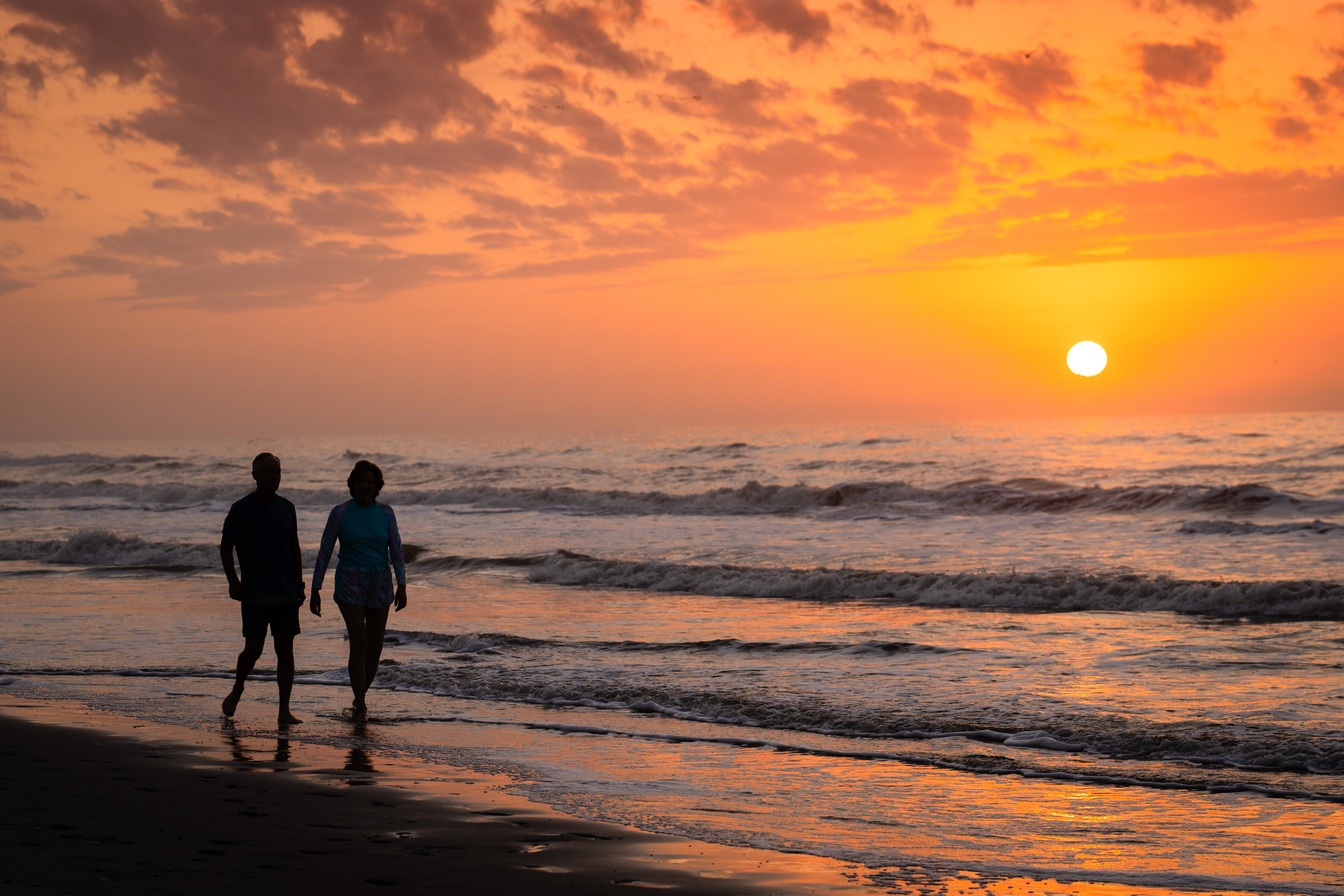 Couple walking at sunset on beach