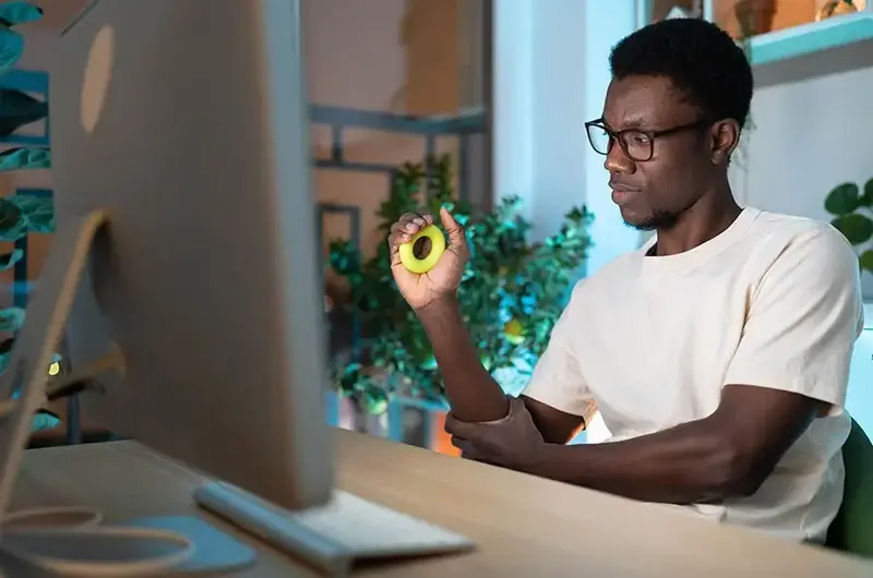 Young African man exercising with silicone grip ring doing hand exercises for Carpal tunnel syndrome prevention