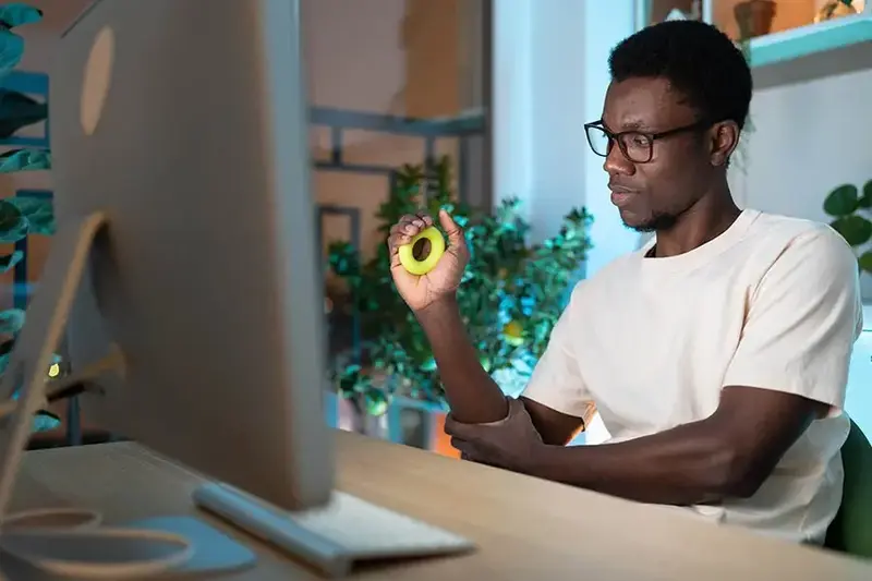 Young African man exercising with silicone grip ring doing hand exercises for Carpal tunnel syndrome prevention