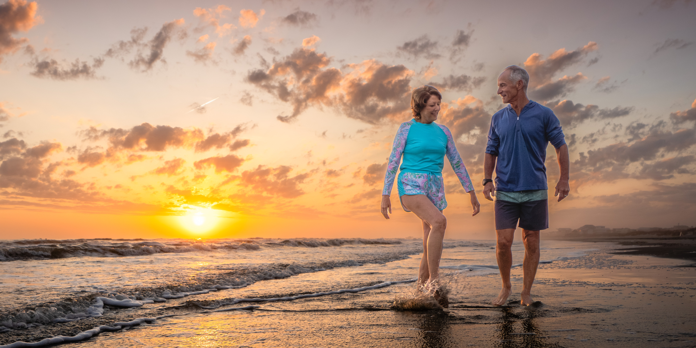 Couple walking on beach at sunrise