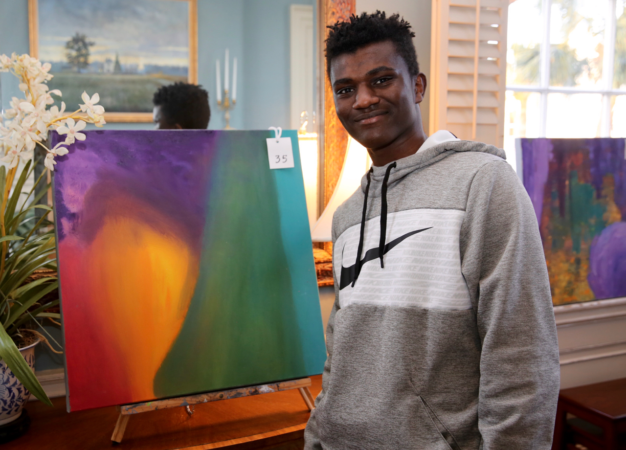 male student standing with artwork