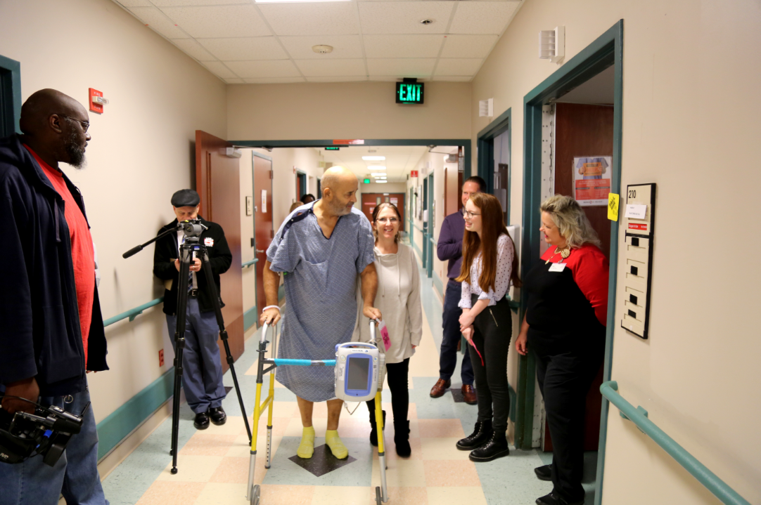 Emily walking with patient in hospital hallway