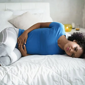 woman on bed with painful period